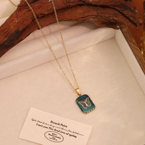 Détail du collier vintage doré avec pendentif papillon en émail vert et écrin velours