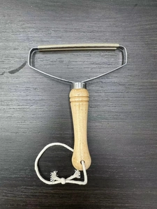 Close-up of portable lint remover with wood handle and pure copper double-sided blade