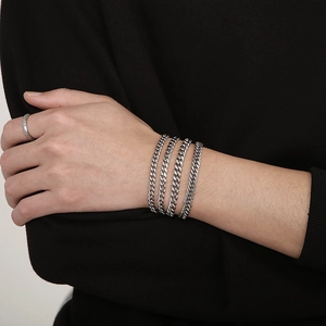 Detailed view of silver stainless steel Cuban chain necklace worn in a multi-layered style