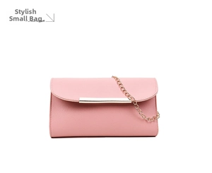 Detail of pink faux leather clutch featuring gold metal bar and delicate chain strap