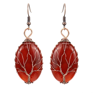 Detailed close-up of handmade tree of life wire-wrapped carnelian earrings in copper