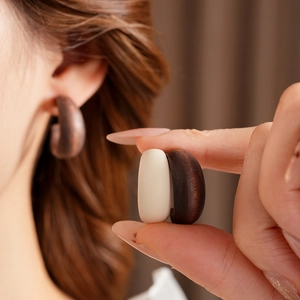 Close-up of minimalist C-shaped wooden earrings with natural wood grain texture