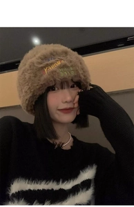 Detail of brown plush knit beanie featuring embroidered letters and soft fur texture