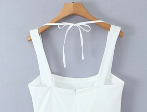 Close-up of white woven dress with wide straps and elegant back bow tie detail