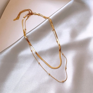 Close-up of double layer gold steel necklace with snake chain on silver silk fabric
