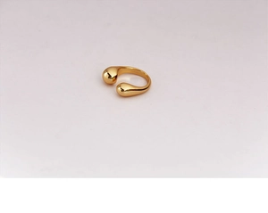 Close-up of golden adjustable open ring with smooth water drop shaped ends and metallic luster