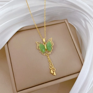 Detail of gold butterfly necklace with green wings and elegant tassel pendant style