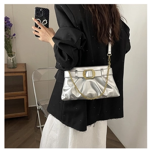 Détail d'un sac hobo plissé argenté avec boucle dorée et bandoulière en chaîne métal