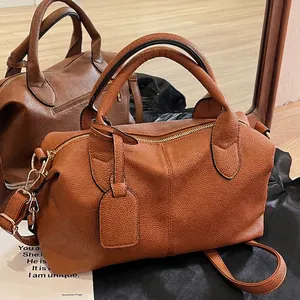 Brown lychee leather Boston shoulder bag with dual handles and mirror reflection view