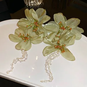 Elegant green fabric flower drop earrings with long beaded tassels on white plate