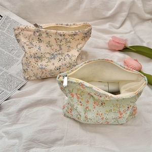 Floral canvas toiletry bag detail with beige and green patterns on white fabric