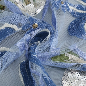 Detailaufnahme der Blumenstickerei und blauen Pailletten auf feinem Netzstoff