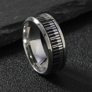 Modern stainless steel ring featuring a black and white piano key design on a stone surface