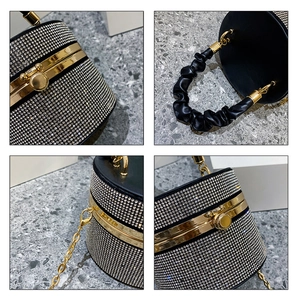 Detail view of black rhinestone bucket bag showing golden hardware and pleated leather handle