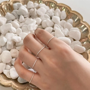 Close-up of four stacked minimalist S925 silver twist rope rings on a luxury tray