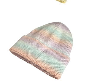 Detailed close-up of rainbow tie-dye gradient knit fabric on a cozy winter beanie