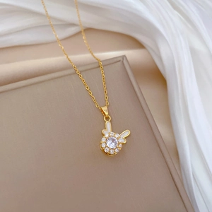 Close-up of golden bunny pendant with white diamonds and enamel on a silk background