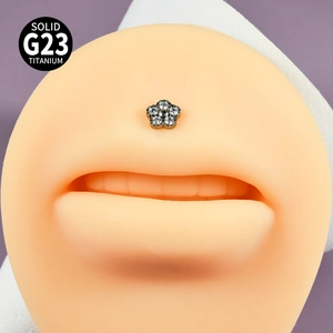 Détail macro du piercing labret en titane G23 avec fleur en zircone porté sur l'oreille