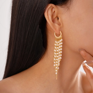 Boucles d'oreilles pendantes élégantes en perles plaquées or 18 carats sur un mannequin