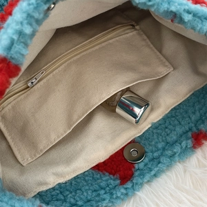 Detail showing plush faux fur texture with metal magnetic buckle and zipper pocket inside