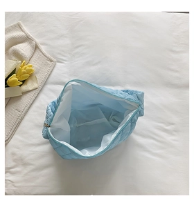Detail view of a spacious light blue quilted bag showing its white inner lining and soft texture
