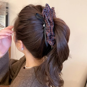 Detailed view of British plaid hair tie with black silk ribbon and diamond accent