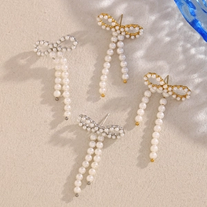 Detail of 18K gold and silver butterfly earrings with long pearl tassel drops
