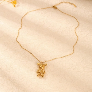 Detailed close-up of golden bear pendant with Peace and Love engravings on beige paper