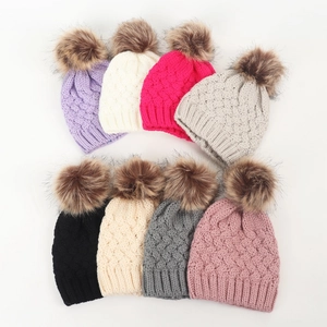 Detailed view of knitted infant hats with large pom-poms in various colors and patterns