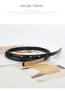 Detailed view of a slim black leather belt with a long gold buckle on a fashion magazine