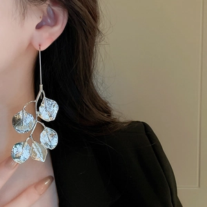 Close-up of silver leaf earrings worn by a model showcasing metallic texture and shine
