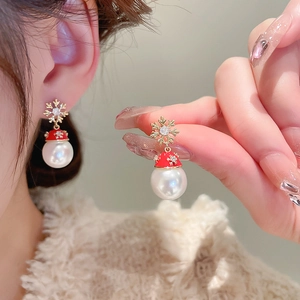 Macro detail of snowflake pearl earrings with red festive hat worn on earlobe