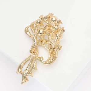 Close-up of the golden brooch back showing a secure pin clasp and detailed floral metalwork