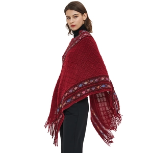 Ethnic knit poncho cape in deep red with colorful trim and fringe tassels on model