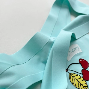 Detailed close-up of seamless mint green fabric with cherry print and fine ribbed texture