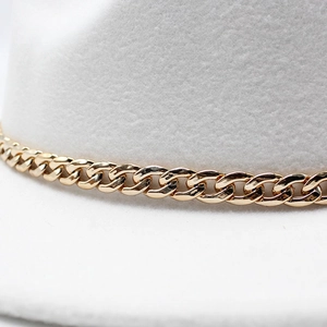 Detailed macro view of white felt fedora hat with elegant gold Cuban link chain trim