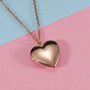 Polished gold heart photo locket necklace displayed on a two-tone pastel background