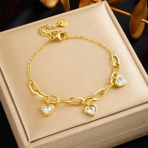 Macro detail of gold-plated chain bracelet featuring three heart-shaped zircon pendants