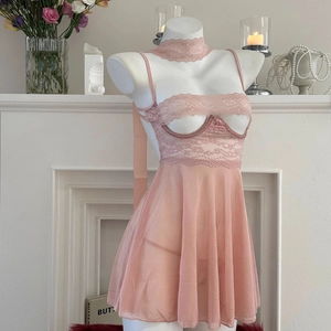 Completo intimo in rete rosa con pizzo e collare abbinato su manichino bianco elegante