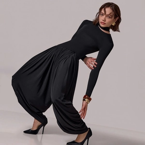 Artistic pose showing black backless jumpsuit with side slit and ruched detail on white background