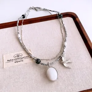 Collier double rang vintage avec pendentif hirondelle argenté et perles sur lin