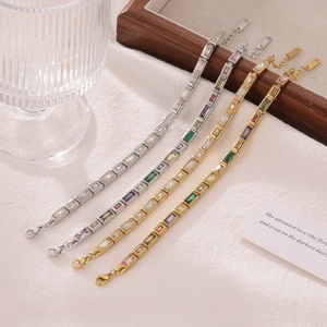 Set of four luxury square zircon bracelets in gold and silver on a white linen surface