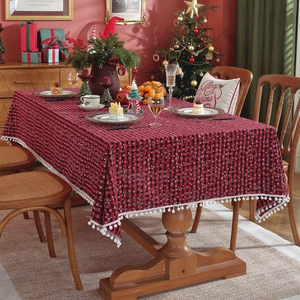 Red and black checkered Christmas tablecloth with white snowflake patterns and pom-pom trim