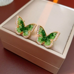 Close-up of gold-plated butterfly earrings with green zircon crystals and fine detailing