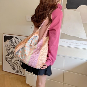 Detail of colorful macrame pattern on a large canvas tote bag worn by a female model