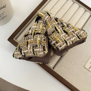 Détail d'une pince à cheveux en tweed avec motif à carreaux et fils argentés fins