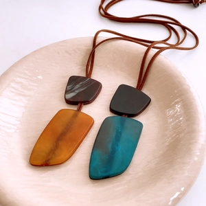Detail of irregular resin necklaces with marble texture on cream ceramic plate