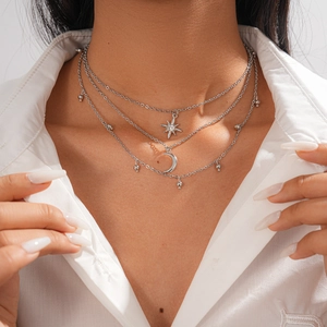 Detail of silver layered necklace with sparkling star and moon pendants on a model