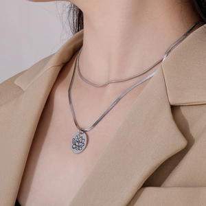 Dettaglio della collana a doppio strato in acciaio inossidabile argento con ciondolo loto