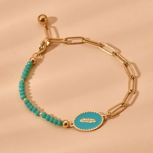 Detailed view of a gold chain bracelet featuring turquoise beads and a leaf-pattern pendant